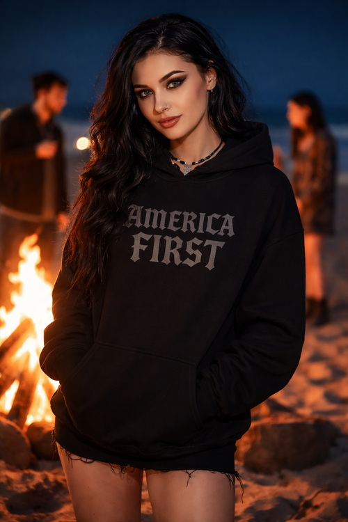 Person wearing a black hoodie with 'AMERICA FIRST' text, standing by a fire.