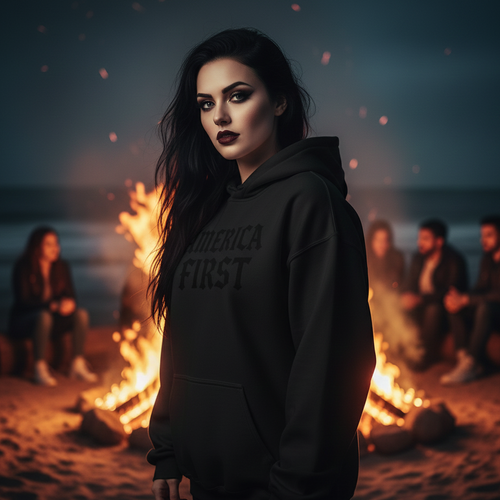 Person wearing a black hoodie with 'AMERICA FIRST' text on a beach at night.