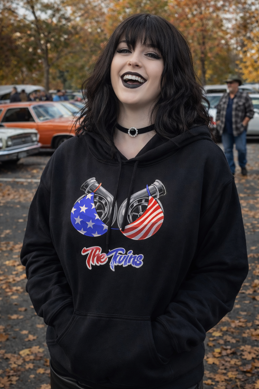 Person wearing a black hoodie with graphic design and text, standing outdoors.