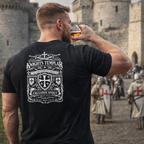 Man wearing a 'Knights Templar' t-shirt in front of a castle with other people in medieval attire.